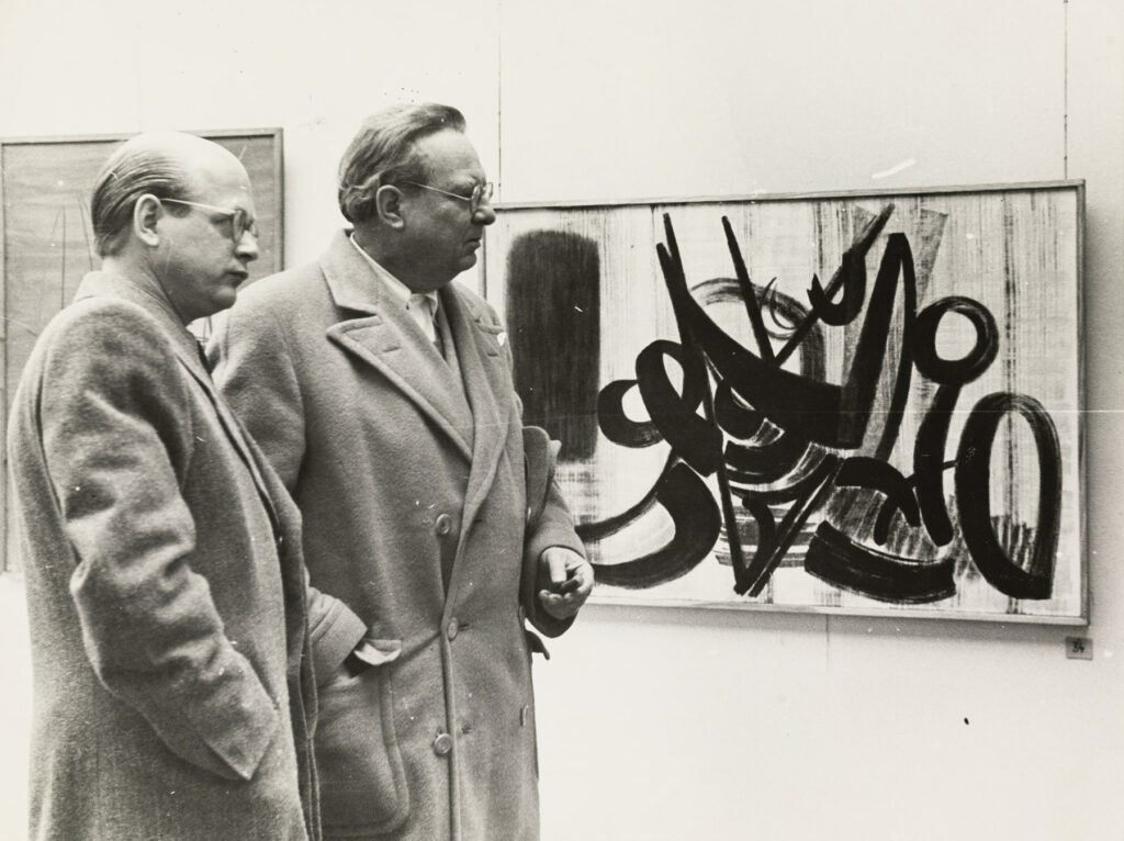 Dr. Ottomar Domnick und Willi Baumeister in einer Ausstellung vor einem Gemälde von Hans Hartung, 1948.