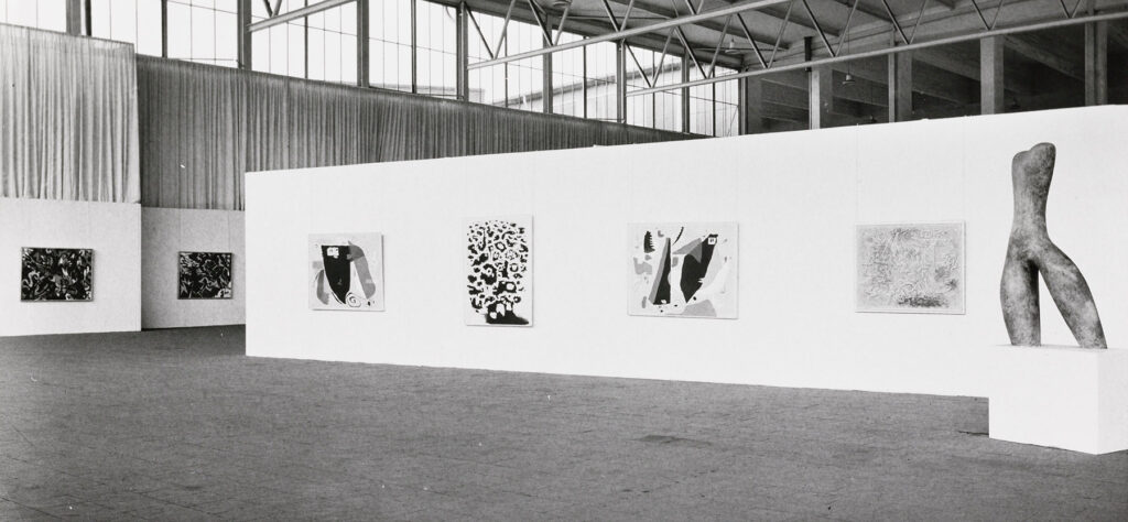 Ausstellungsansicht in einer Halle, Stellwände mit Werken