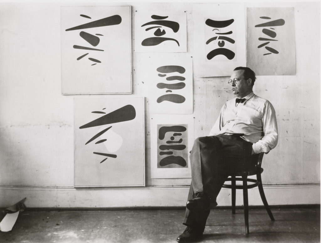 Baumeister sitzend vor einer Wand mit Bildern