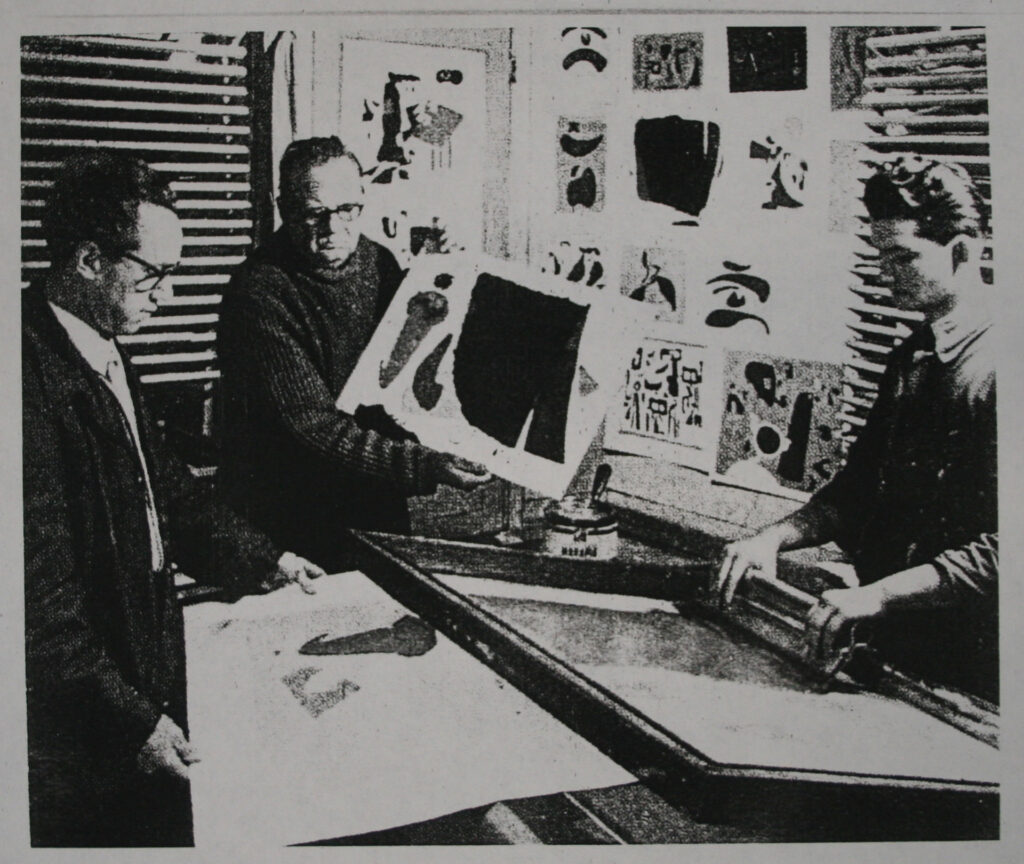 Willi Baumeister mit zwei anderen Personen in der Druckerei Domberger