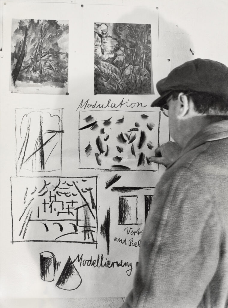 Willi Baumeister vor einer Wand mit Anschauungszeichnungen