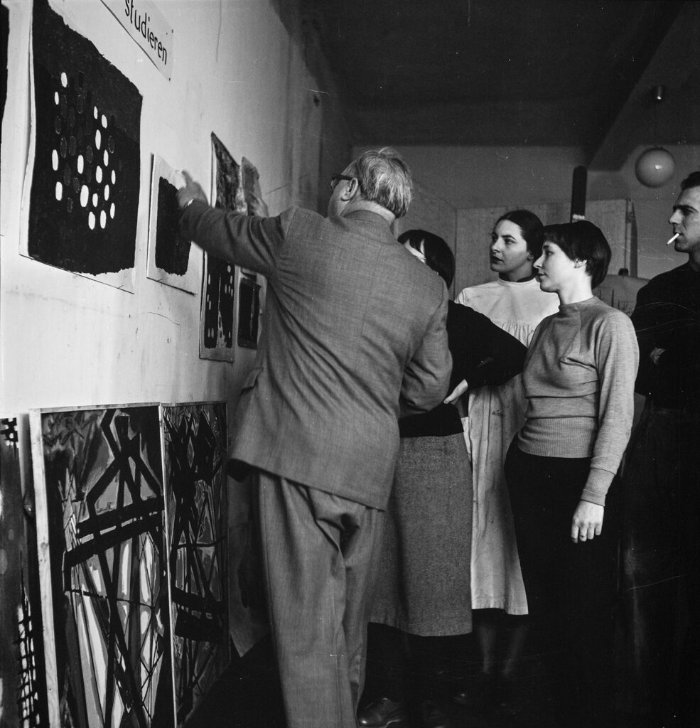 Willi Baumeister in Rückansicht mit anderen Personen in einer Ausstellung, Bilder betrachtend