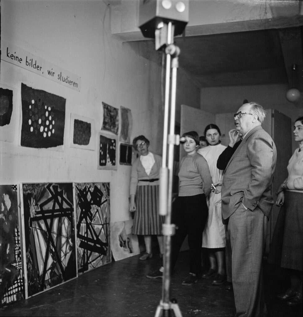 Gruppe von Studierenden mit Willi Baumeister Wand mit Werken betrachtend