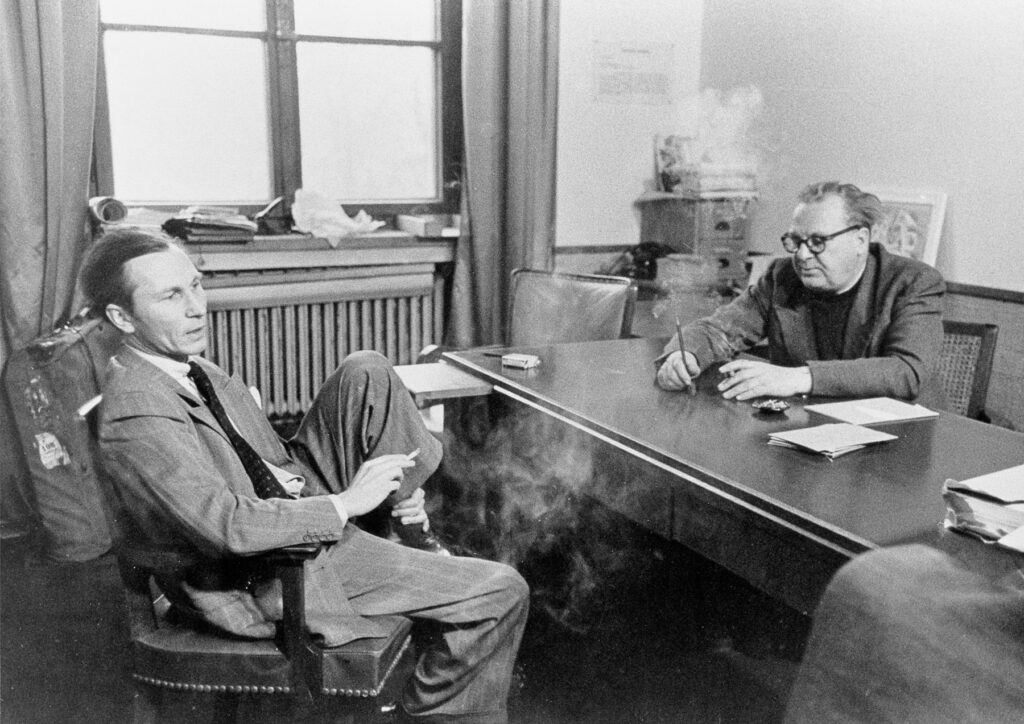 Willi Baumeister rauchend an einem Tisch mit Dr. Hans Konrad Röthel sitzend