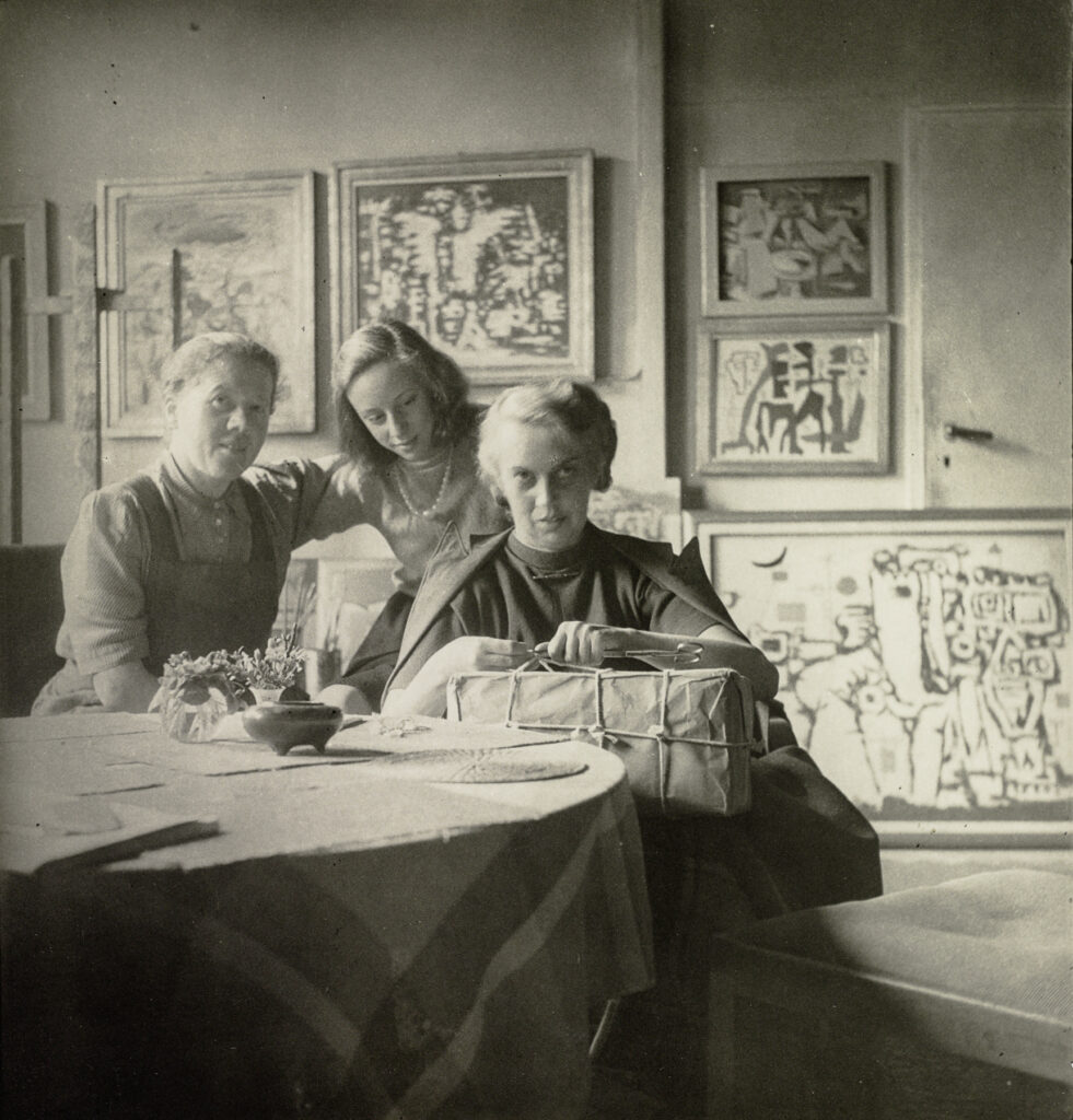 Marie Dobler mit Felicitas und Margrit Baumeister um einen Tisch sitzend und Geschenke auspackend